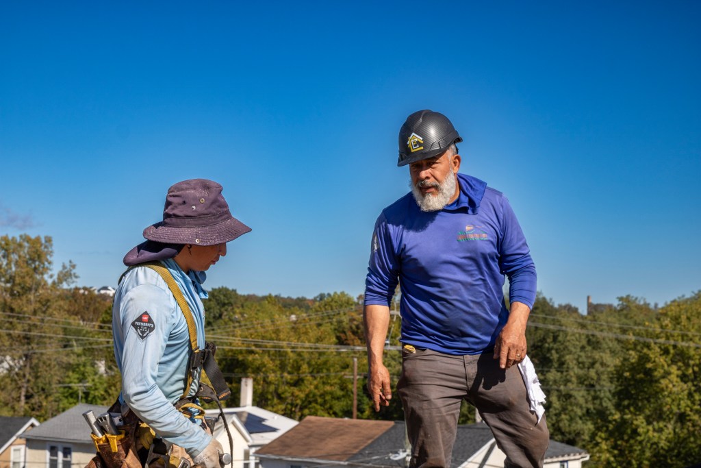 Project Manager Marco explaining roofing steps to crew member
